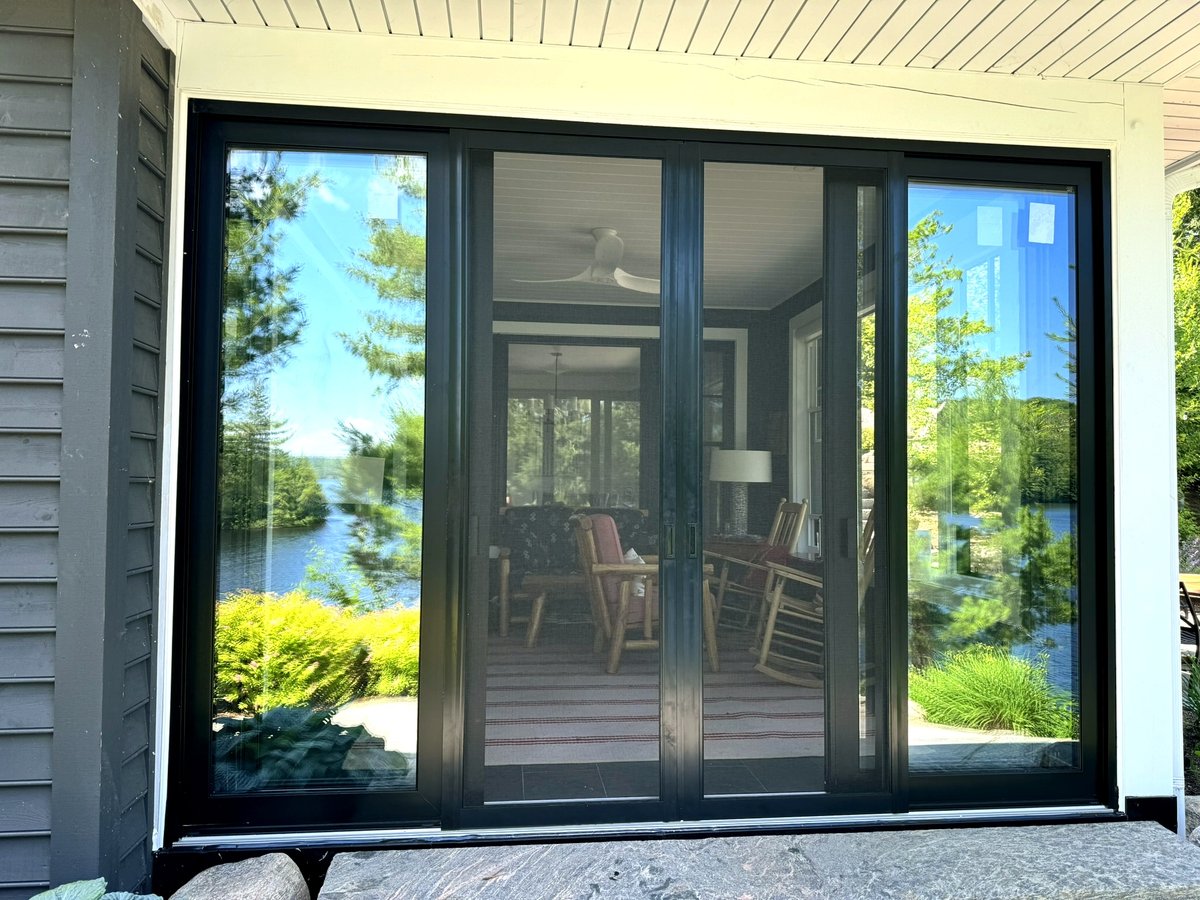 Black-framed sliding patio doors opening onto a screened porch overlooking a lake