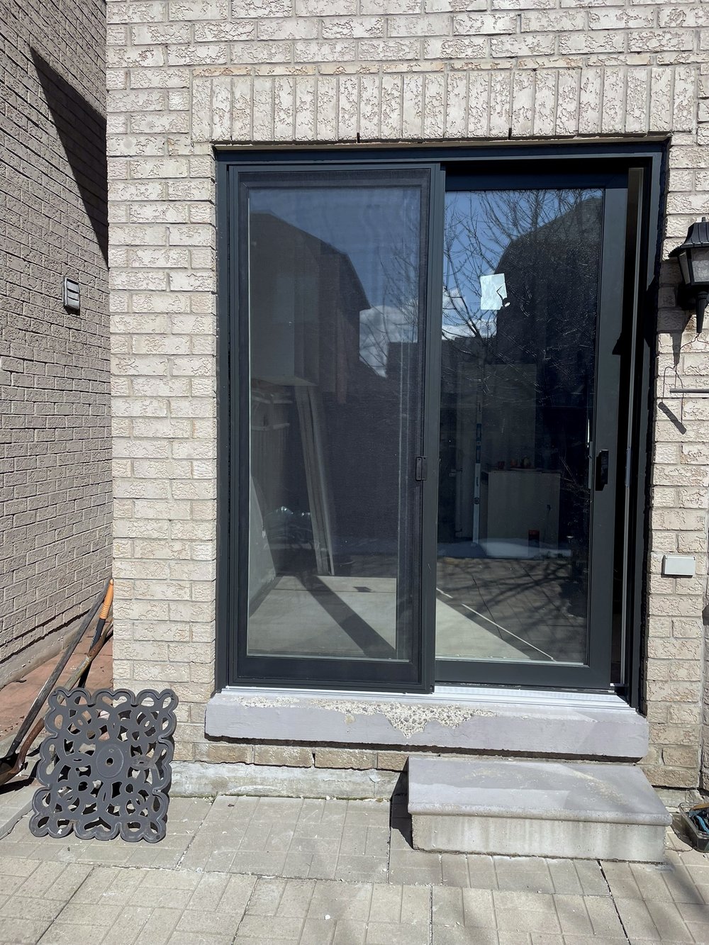 Black-framed sliding patio door on a stone home exterior