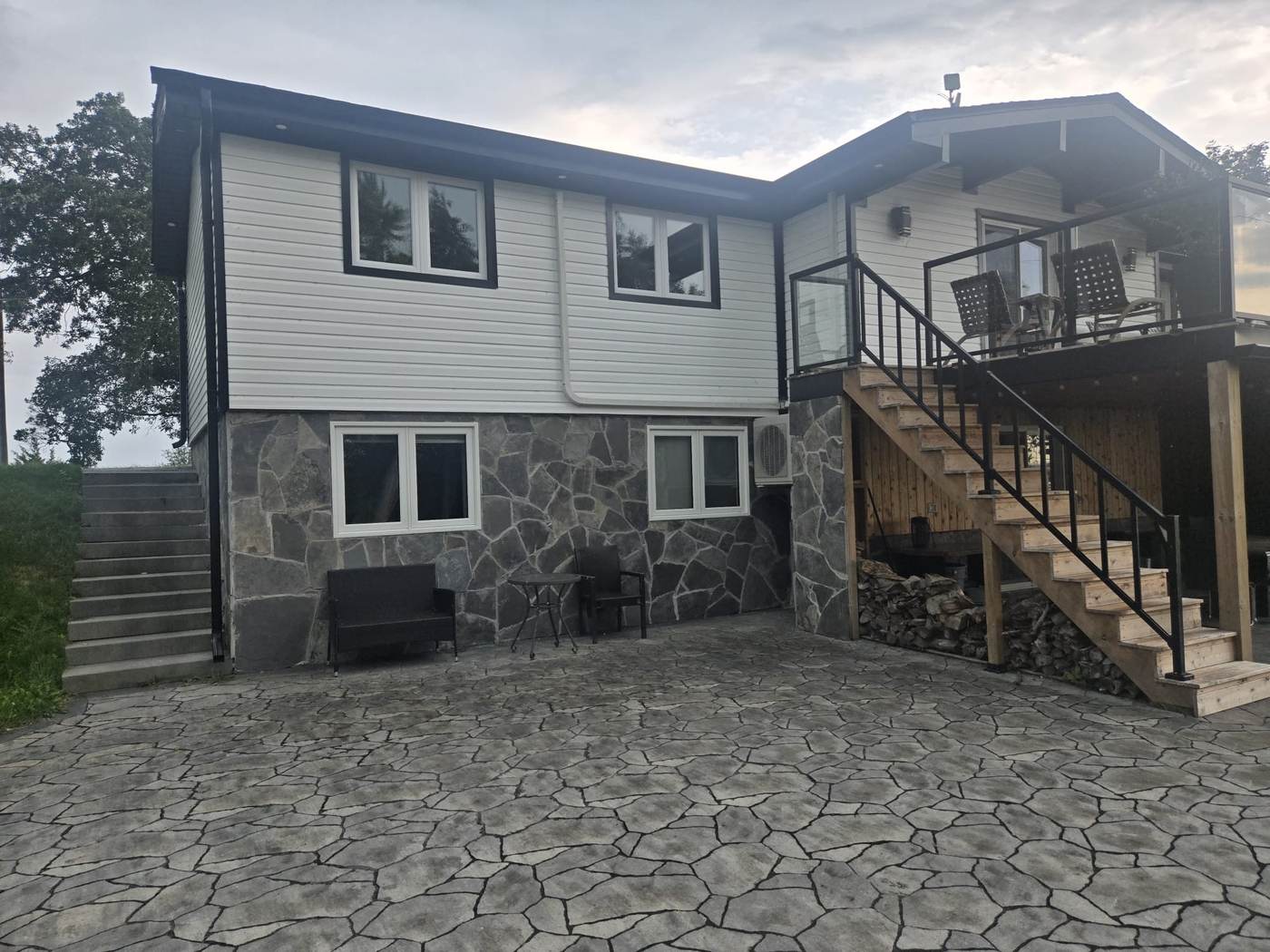 Rear elevation of a home with new vinyl windows and a deck, showing a completed whole-elevation window replacement