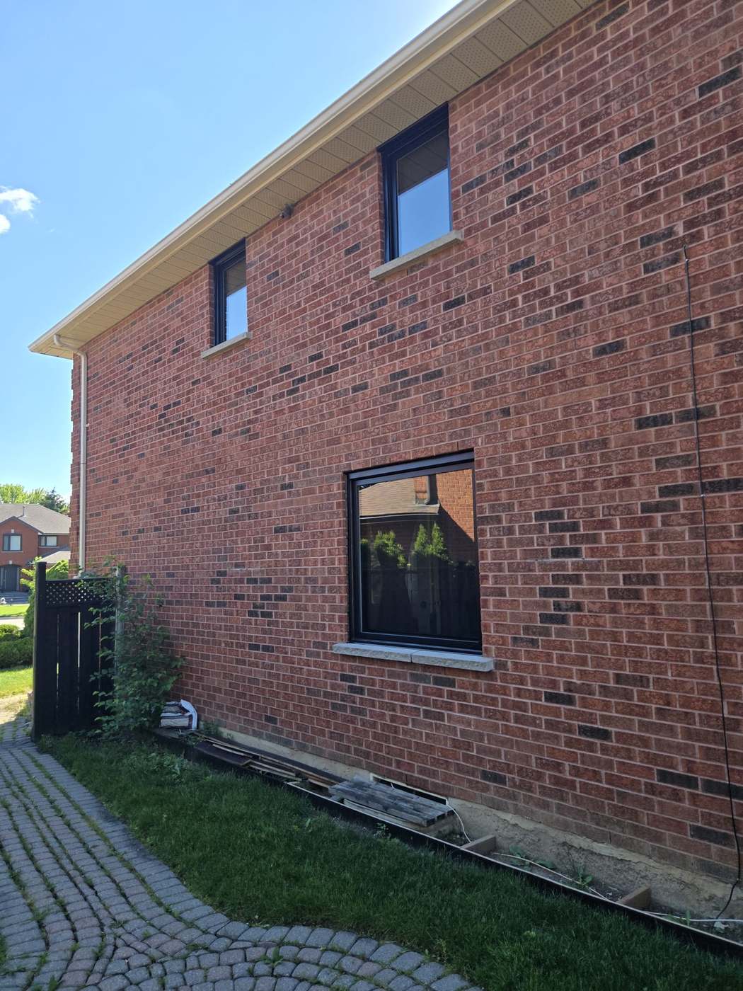 Black-framed vinyl windows installed across the elevation of a red brick two-storey home, typical of Brampton subdivision housing
