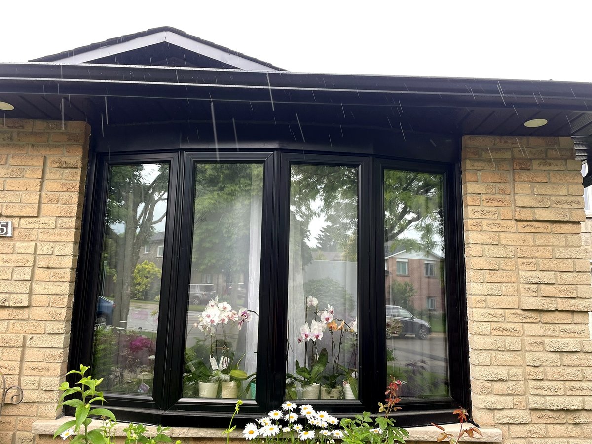 Black-framed bow window with four panels on a brick home