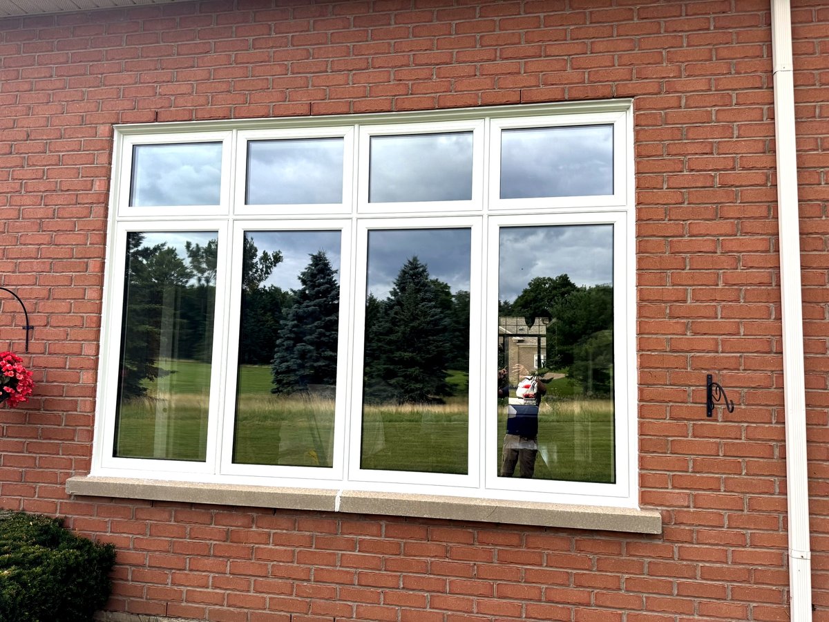 Four-panel white vinyl casement windows installed on a red brick home