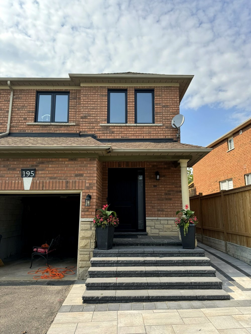 White and black garage doors on a brick home, with windows in the upper gable dormers